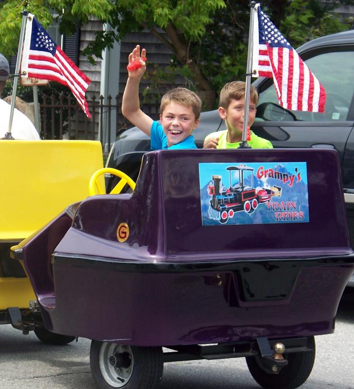 Two boys wave from the back car of "Grampy's Train Ride" during Harbor Days on Saturday afternoon. BY MATTHEW BERNAT
